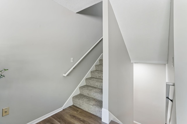 stairway with wood finished floors and baseboards
