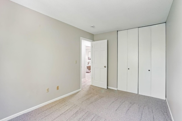 unfurnished bedroom featuring carpet, baseboards, and a closet
