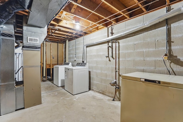 unfinished basement featuring washing machine and dryer and refrigerator