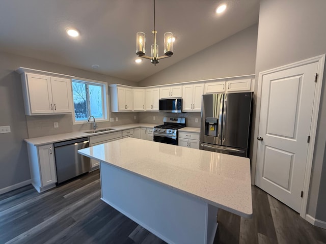 kitchen featuring appliances with stainless steel finishes, a sink, a chandelier, white cabinets, and lofted ceiling