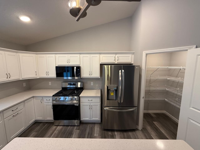 kitchen featuring appliances with stainless steel finishes, lofted ceiling, dark wood-type flooring, white cabinetry, and light countertops
