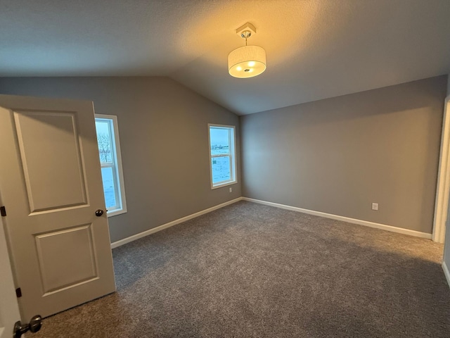 bonus room featuring vaulted ceiling, dark carpet, and baseboards