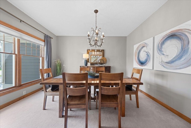 dining area with light colored carpet, a chandelier, and baseboards