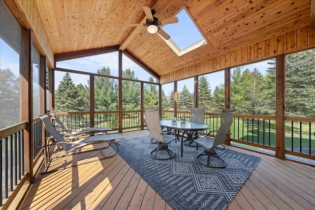 sunroom with ceiling fan, outdoor dining area, a skylight, and view of scattered trees