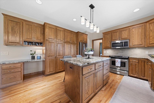kitchen with appliances with stainless steel finishes, brown cabinetry, light wood finished floors, and recessed lighting