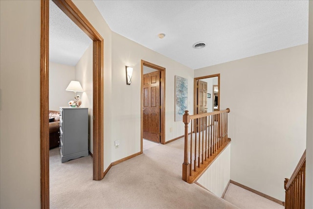 hall featuring an upstairs landing, light colored carpet, and baseboards