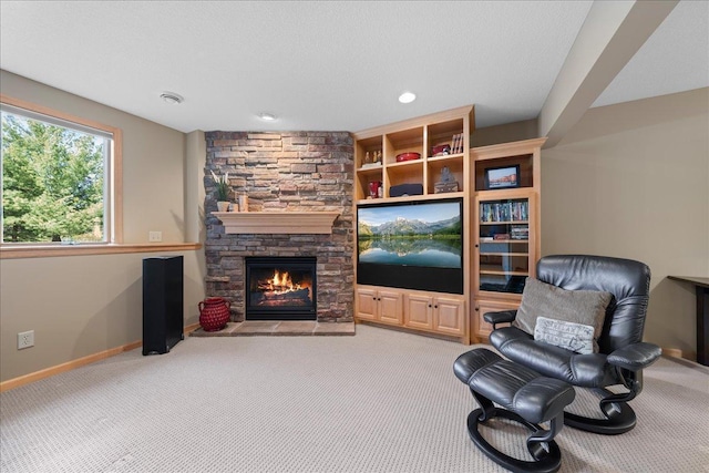 living area featuring carpet, a stone fireplace, baseboards, and recessed lighting