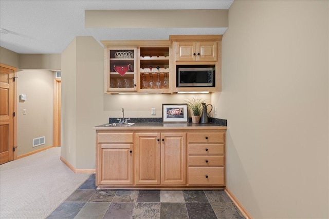 indoor wet bar with stainless steel microwave, baseboards, and dark stone finish flooring