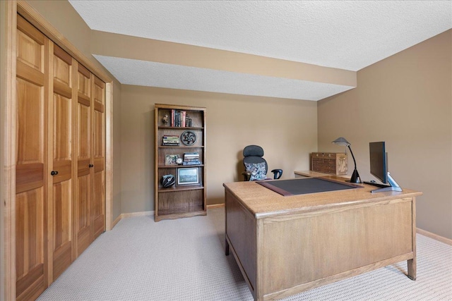 home office featuring light carpet, baseboards, and a textured ceiling