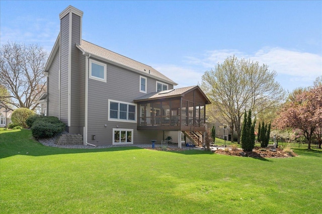 rear view of property featuring a sunroom, stairs, a chimney, and a yard
