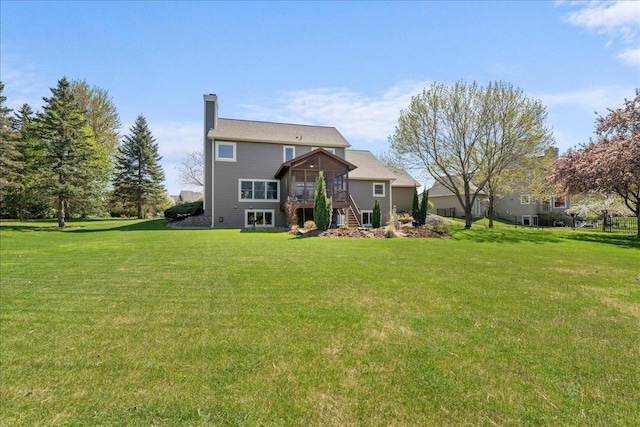 rear view of house with a sunroom, a yard, and a chimney