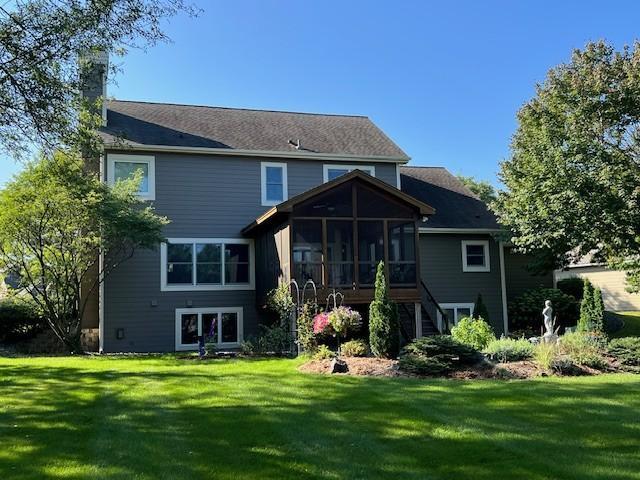 back of house featuring a sunroom, a yard, stairs, and a chimney