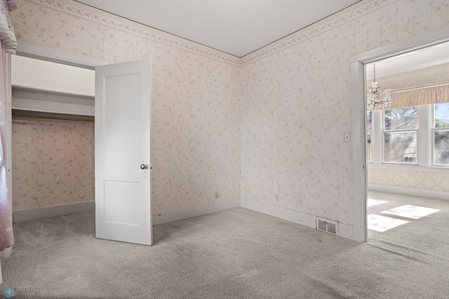 unfurnished bedroom featuring carpet flooring, wallpapered walls, and a chandelier