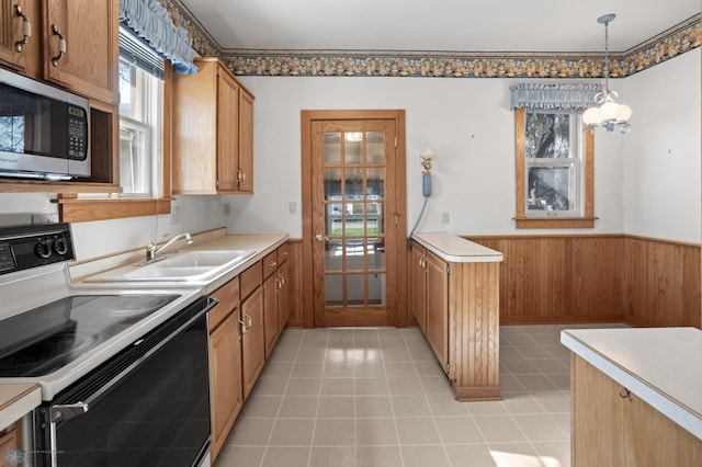 kitchen featuring electric range, stainless steel microwave, wainscoting, a sink, and brown cabinets