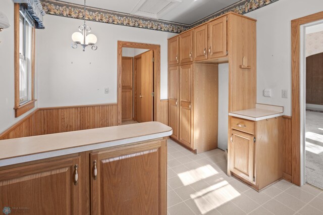kitchen with wainscoting, light countertops, pendant lighting, and wood walls