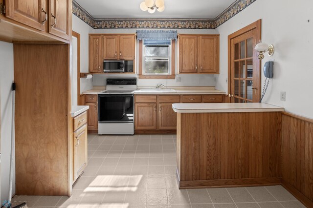 kitchen featuring electric stove, stainless steel microwave, light countertops, and brown cabinets