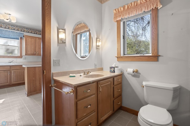 bathroom with toilet, vanity, tile patterned floors, and baseboards