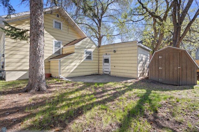rear view of property with a shed, a patio area, and an outdoor structure