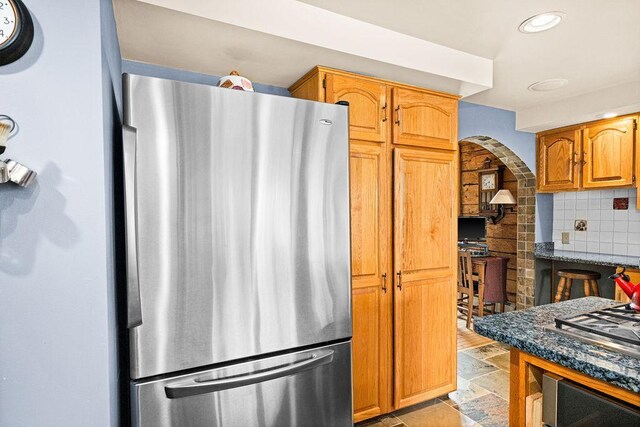 3213 Alger Grade, Silver Creek Twp, MN 55616 - kitchen with freestanding refrigerator, backsplash, arched walkways, recessed lighting, and dark stone countertops