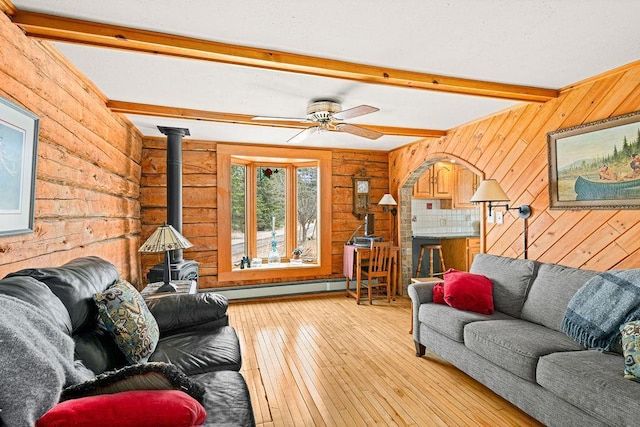 3213 Alger Grade, Silver Creek Twp, MN 55616 - living area featuring wooden walls, beamed ceiling, light wood-style flooring, a wood stove, and a baseboard radiator