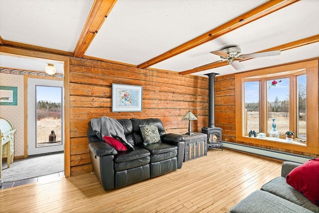 3213 Alger Grade, Silver Creek Twp, MN 55616 - living area featuring a wood stove, beam ceiling, baseboard heating, wood-type flooring, and a ceiling fan