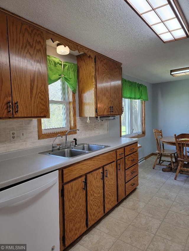 kitchen featuring dishwasher, a sink, backsplash, light countertops, and a textured ceiling