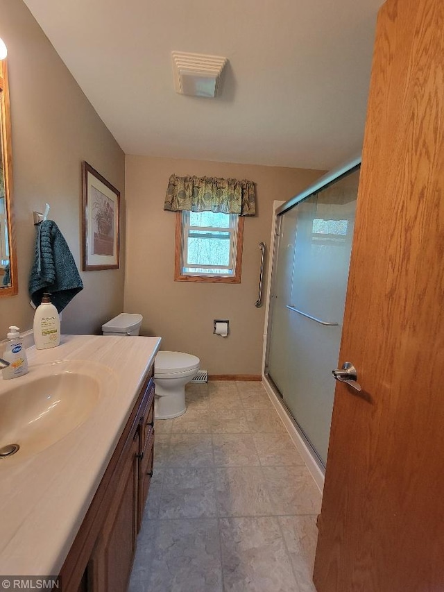 full bath with a shower stall, vanity, toilet, and baseboards