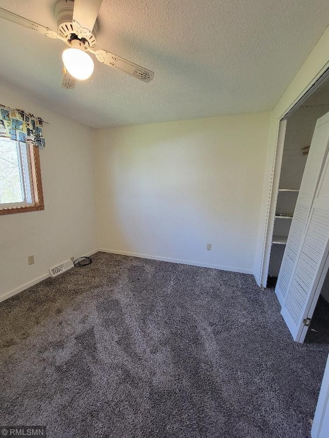 unfurnished room with carpet floors, a ceiling fan, a textured ceiling, and baseboards