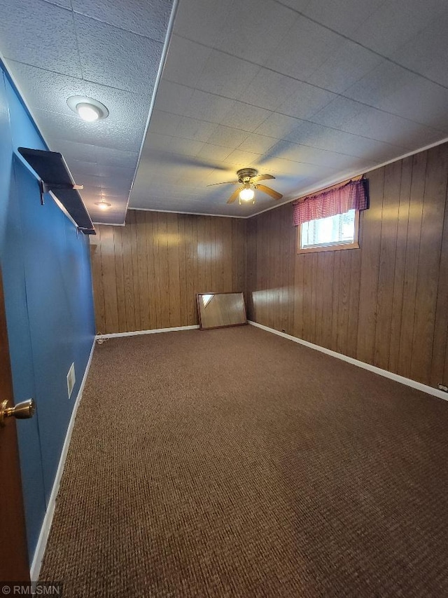 empty room with baseboards, wooden walls, and carpet