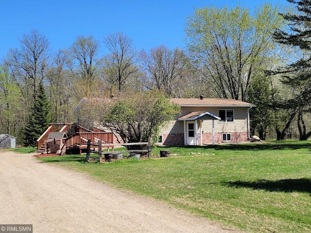 view of front of property featuring a front yard, brick siding, a deck, and stairway