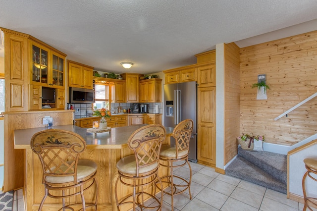 12235 323rd St, Princeton, MN 55371 - kitchen with stainless steel appliances, wood walls, a breakfast bar, a textured ceiling, and glass insert cabinets