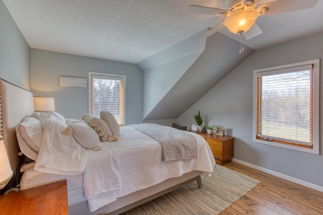 12235 323rd St, Princeton, MN 55371 - bedroom featuring light wood finished floors, multiple windows, baseboards, ceiling fan, and a textured ceiling
