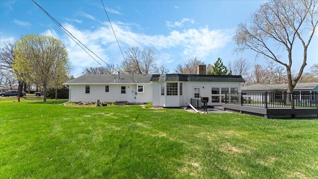 rear view of house featuring a chimney, a deck, and a yard