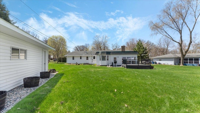 back of house with a yard, a chimney, and a wooden deck