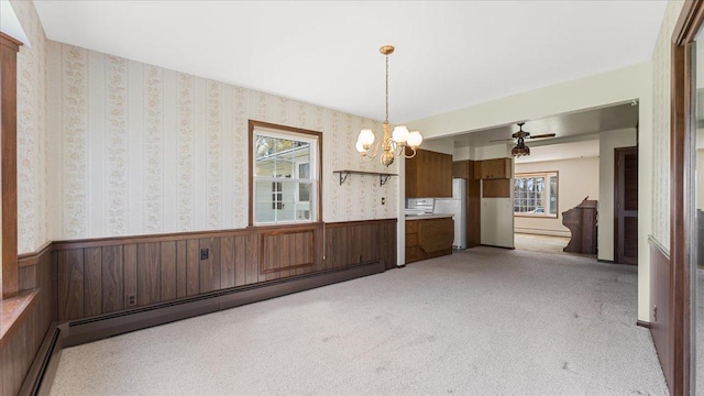 unfurnished dining area featuring a baseboard radiator, a wainscoted wall, light colored carpet, a chandelier, and baseboard heating