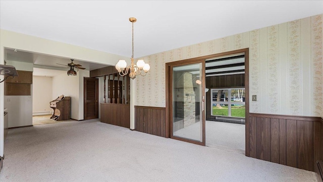 unfurnished dining area featuring wainscoting, wallpapered walls, carpet flooring, a chandelier, and a baseboard heating unit