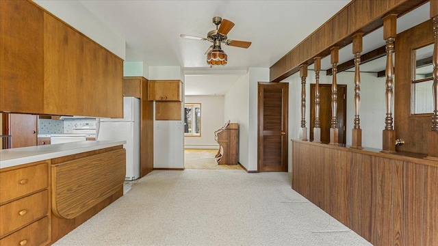 kitchen with brown cabinetry, a ceiling fan, light colored carpet, light countertops, and freestanding refrigerator