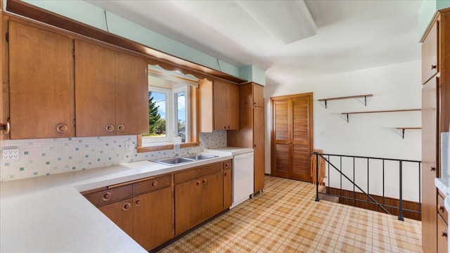 kitchen with a sink, white dishwasher, light countertops, light floors, and backsplash