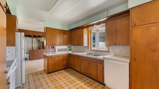 kitchen featuring white appliances, a sink, light floors, light countertops, and brown cabinetry