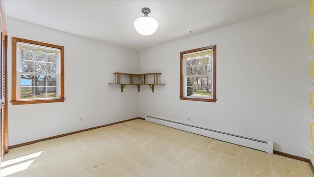 empty room with baseboard heating, plenty of natural light, light carpet, and baseboards