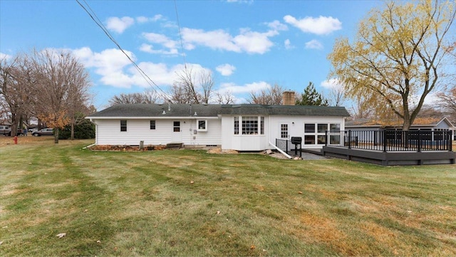 back of house with a chimney, a deck, and a lawn