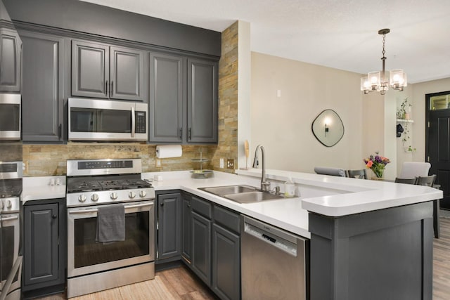 17208 72nd Ave N, Maple Grove, MN 55311 - kitchen featuring stainless steel appliances, a peninsula, a sink, light wood finished floors, and decorative backsplash
