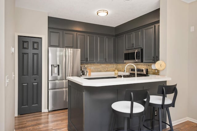 17208 72nd Ave N, Maple Grove, MN 55311 - kitchen with appliances with stainless steel finishes, a peninsula, tasteful backsplash, dark wood-type flooring, and baseboards