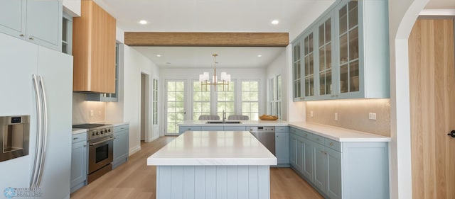 kitchen with appliances with stainless steel finishes, a sink, light wood-type flooring, a center island, and a peninsula