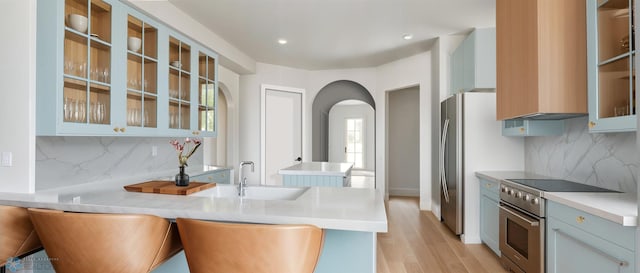 kitchen featuring high end stainless steel range, a sink, decorative backsplash, arched walkways, and recessed lighting