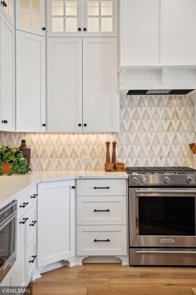 13708 Park Haven Trl, Prior Lake, MN 55372 - kitchen with stainless steel appliances, white cabinetry, premium range hood, light stone counters, and decorative backsplash
