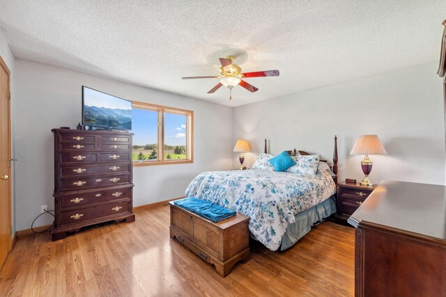 bedroom featuring wood finished floors, a textured ceiling, baseboards, and ceiling fan