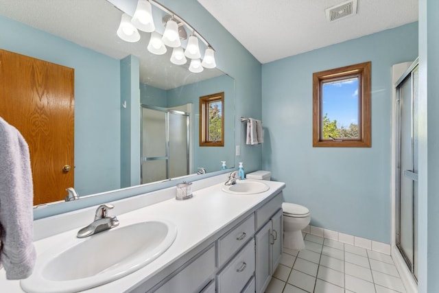 full bath with a stall shower, tile patterned floors, double vanity, toilet, and baseboards