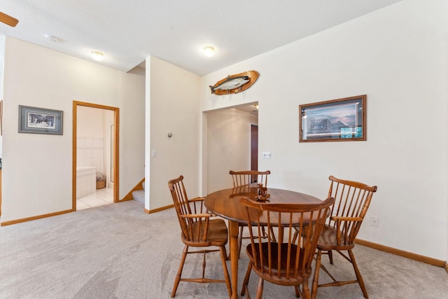dining room featuring light colored carpet, baseboards, and stairs