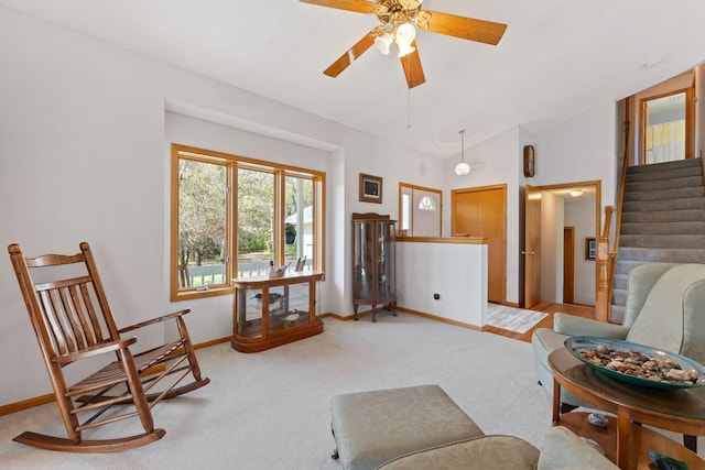 living area featuring ceiling fan, light colored carpet, baseboards, stairway, and lofted ceiling